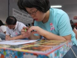 Anak-anak perempuan penyandang Down's Syndrome sedang menggambar dalam lomba gambar di Jakarta, 5 Desember 2004. (Foto: AP)