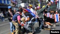曼谷的反政府抗议者把一名受伤的同伴抬离爆炸袭击现场。（2014年1月17日）