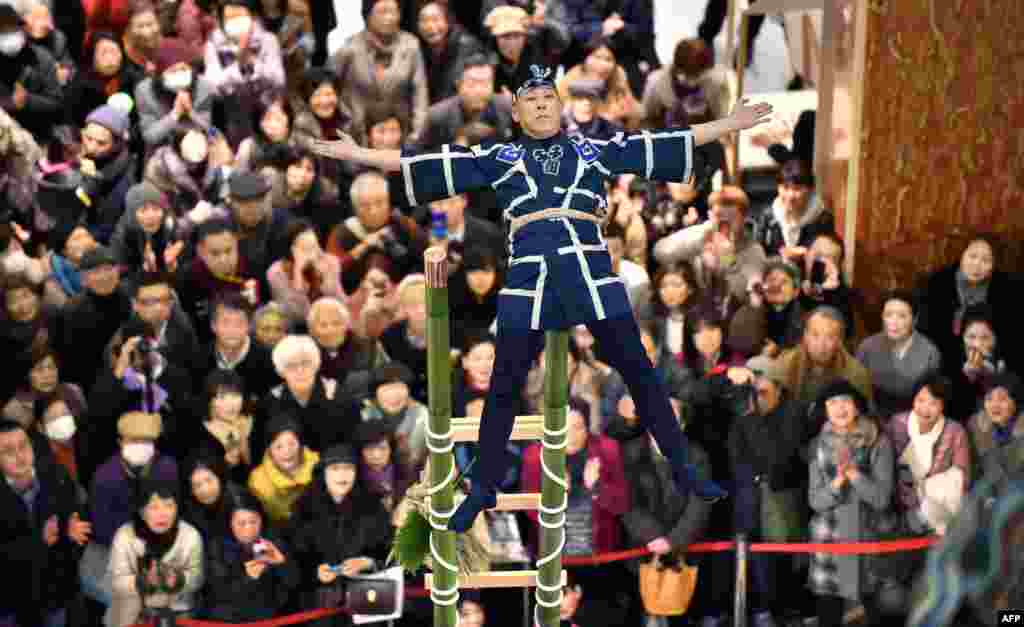 일본 도쿄에서 열린 신년 축하 행사에서 전통 소방수 복장을 한 남성이 대나무 사다리 위에서 공연을 하고 있다.