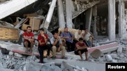 Người dân Palestine ngồi trên đống đổ nát từ những ngôi nhà bị phá hủy trong khu vực Shejaia ở thành phố Gaza 6/8/2014.