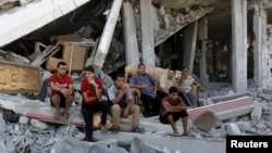 8月6日巴勒斯坦人坐在加沙被毁坏的住房废墟中
