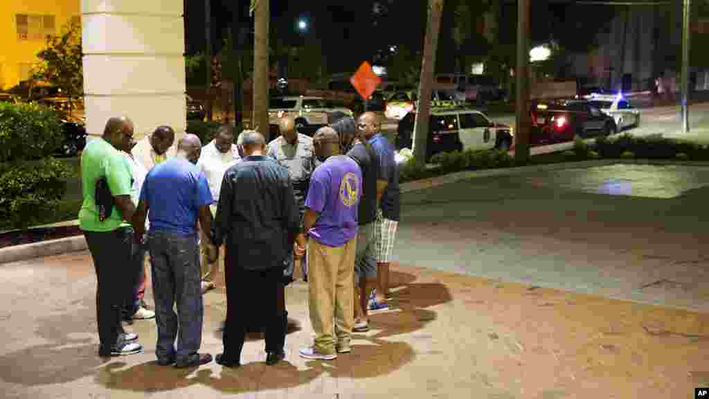 Worshippers gather to pray in a hotel parking lot across the street from the scene of a shooting Wednesday, June 17, 2015.