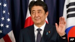 FILE - Japanese Prime Minister Shinzo Abe gestures as he meets with U.S. President Donald Trump and South Korean President Moon Jae-in before the Northeast Asia Security dinner in Hamburg, July 6, 2017. His poll numbers have bounced back to around 50 perc