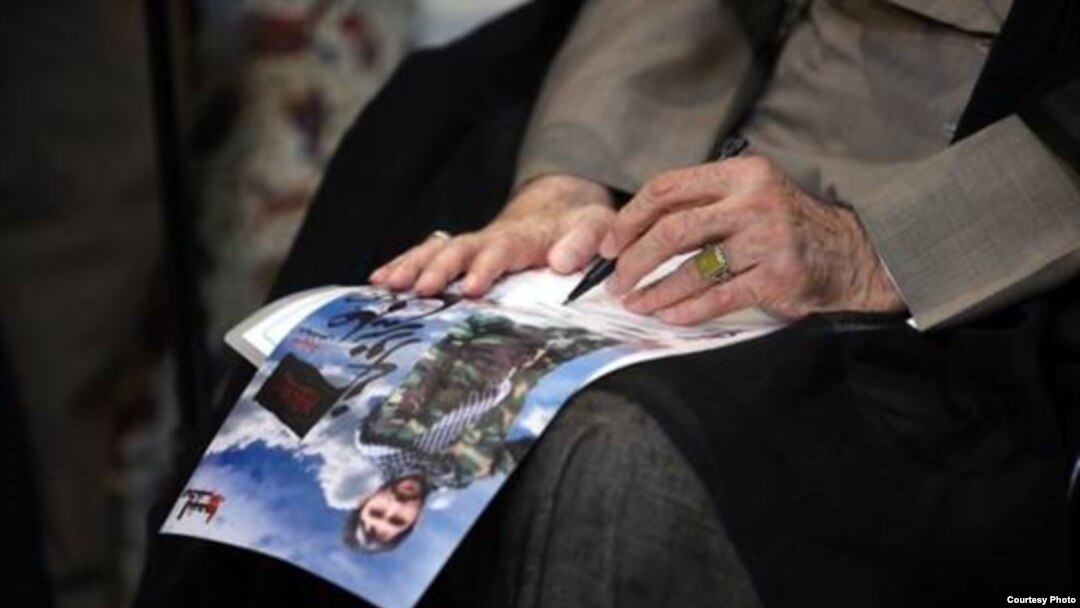 A photo shows Iran’s supreme leader, Ayatollah Ali Khamenei, signing a poster of a fallen shrine defender. Source: Khamenei.ir
