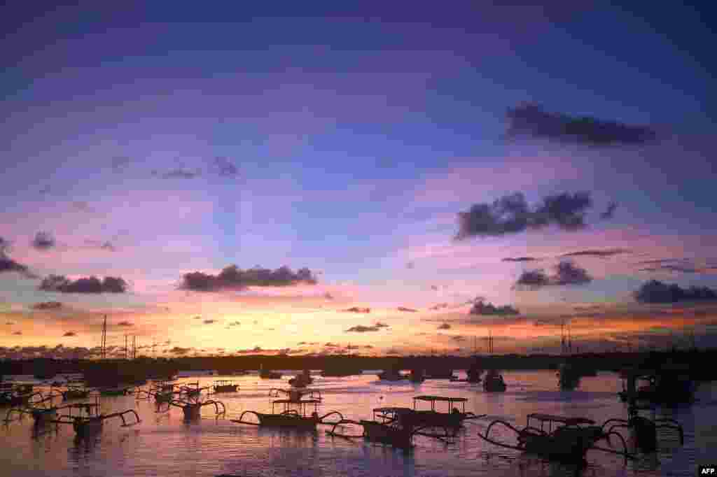 Traditional boats are anchored at a small port during sunset on Serangan island in Denpasar on Indonesia's resort island of Bali on March 9, 2018.