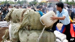 A Cambodian officer, right, pours fuel into some three tones of various drugs are seized in the nation wide of this country at the outskirt of Phnom Penh, Cambodia, file photo. 