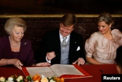 FILE - Queen Beatrix (L) of the Netherlands passes the act of abdication to her son Crown Prince Willem-Alexander next to his wife Crown Princess Maxima (R) during a ceremony at the Royal Palace in Amsterdam, April 30, 2013.