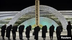 Keluarga korban bencana gempa bumi dan tsunami memberi hormat ke hadapan altar bertabur bunga chrysanthemums dalam peringatan tiga tahun bencana nasional tersebut di Tokyo (11/3).