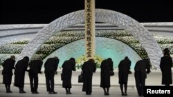 Relatives of victims of the March 11, 2011 earthquake and tsunami bow to the altar as they offer chrysanthemums for the victims at the national memorial service in Tokyo, March 11, 2014.