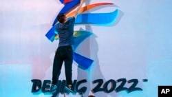 FILE - A crew member fixes a logo for the 2022 Beijing Winter Olympics before a launch ceremony to reveal the motto for the Winter Olympics and Paralympics in Beijing on Sept. 17, 2021. 
