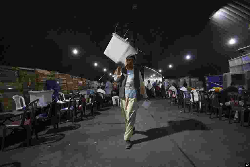 An Afghan election worker carries a box of presidential run-off ballots for the audit process at an election commission office in Kabul, Afghanistan, Aug. 25, 2014.