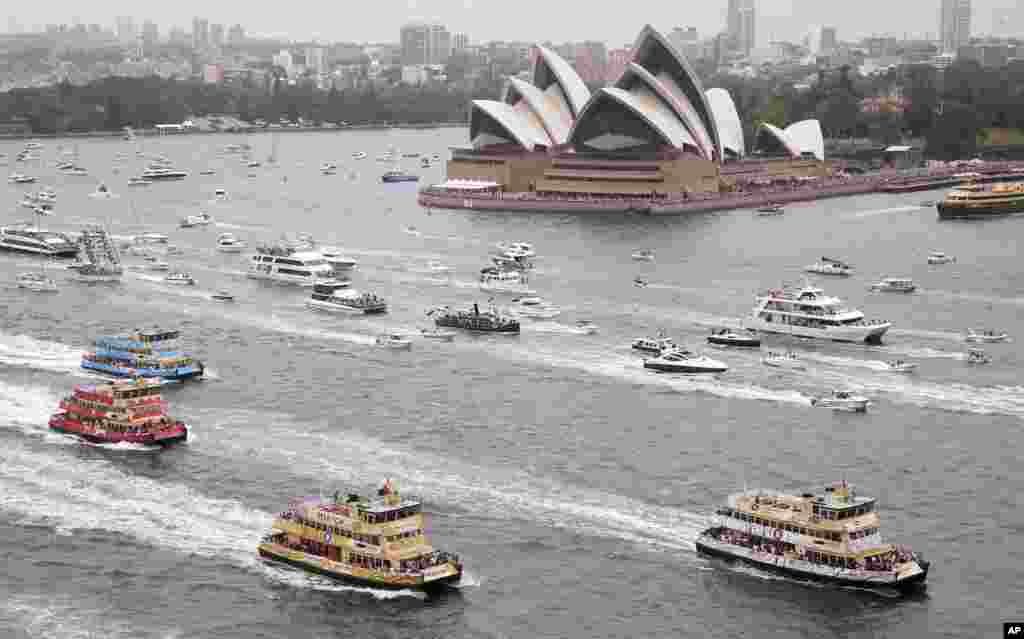 Competitors in the annual ferry boat race are supported by a spectator flotilla as they cruise past the Sydney Opera House as part of Australia Day celebrations in Sydney.