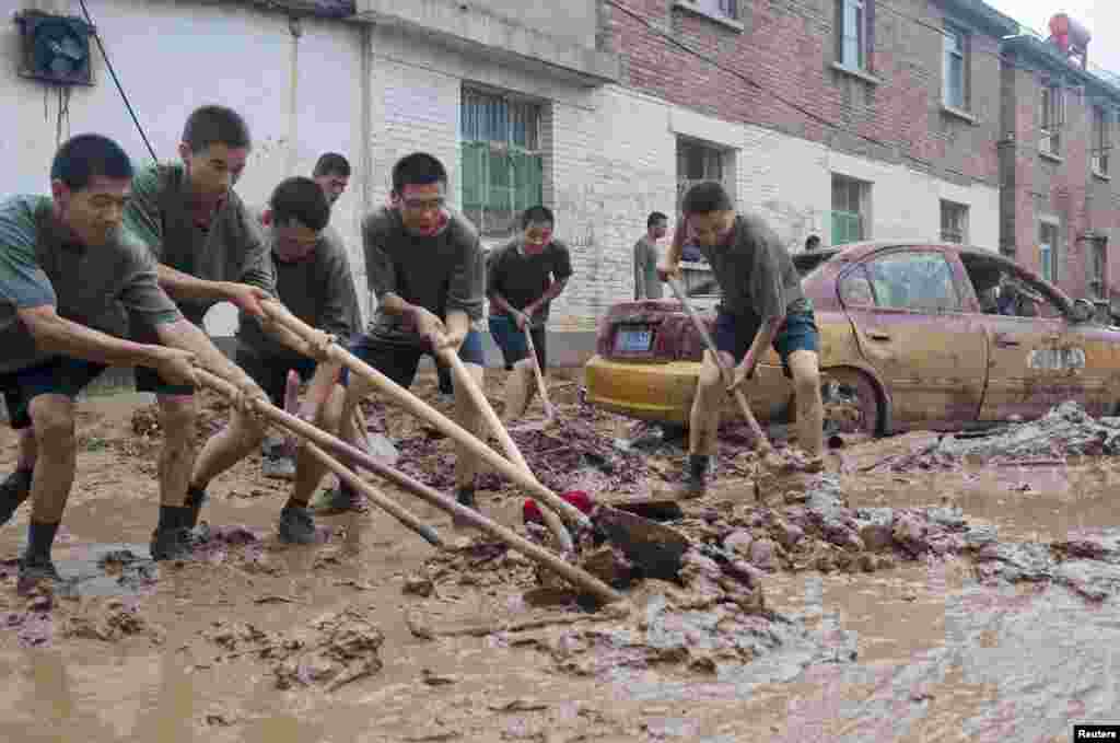 Chinese People&#39;s Liberation Army soldiers clear mud from a street in a flood-hit area in Hougoumen village of Fangshan district in Beijing, July 25, 2012. 