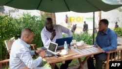 FILE - Men work on their laptops at the Endiro Cade in Kampala. 