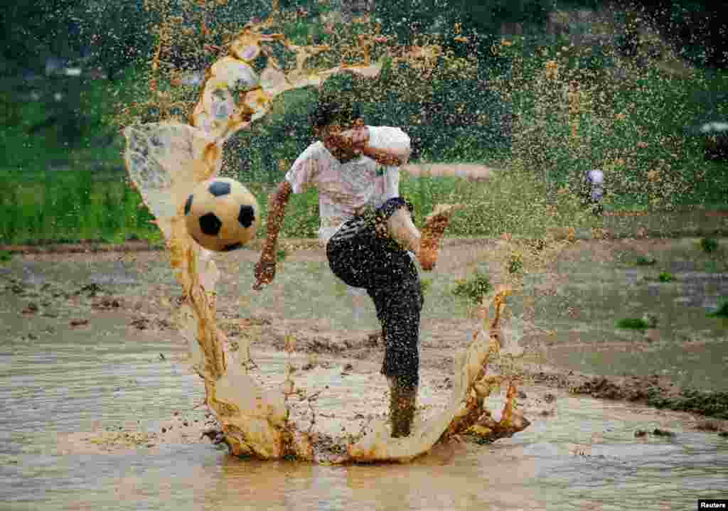 A man kicks a football as he takes part in an event celebrating National Paddy Day, also called Asar Pandra, that marks the commencement of rice crop planting in paddy fields as monsoon season arrives, in Lalitpur, Nepal.