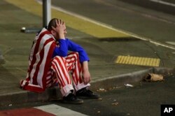 A man dressed in red-white-and-blue sits on the curb during a protest against President-elect Donald Trump in Seattle's Capitol Hill neighborhood, Nov. 9, 2016.