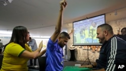Carlos Junior celebrates at the end of the match between Brazil and Mexico with the help of an interpreter who used tactile signing and a model soccer field to recount the passes, goals and fouls of Brazil's 2-0 victory.