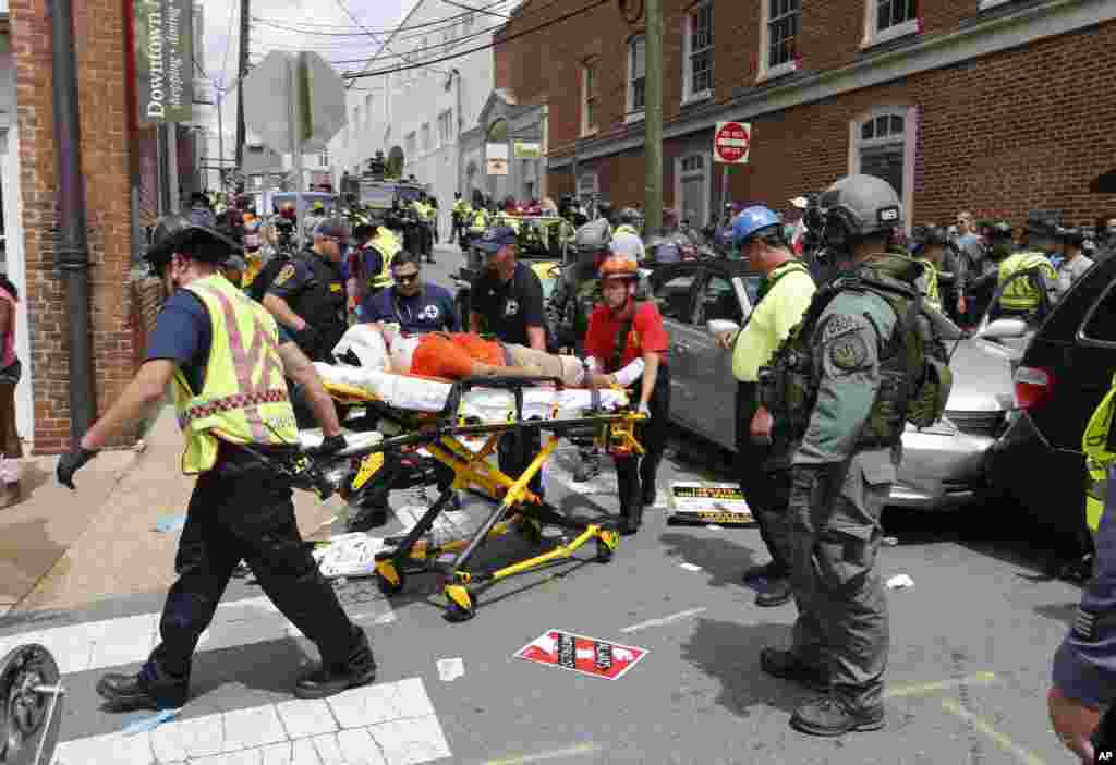 Rescue personnel help injured people after a car ran into a large group of protesters after a white nationalist rally in Charlottesville, Aug. 12, 2017.