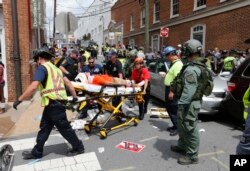 FILE - Rescue personnel help injured people after a car ran into a large group of protesters after an white nationalist rally in Charlottesville, Va., Aug. 12, 2017.
