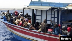 FILE - Illegal migrants who attempted to sail to Europe, sit in a boat carrying them back to Libya, after their boat was intercepted at sea by the Libyan coast guard, at Khoms, Libya, May 6, 2015.