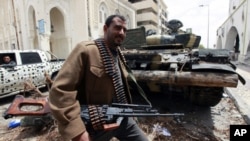 A rebel fighter walks beside a captured Gaddafi forces tank in Tripoli street April 22, 2011. Rebel fighters pushed Gaddafi forces off the upper part of Tripoli Street in central Misrata during an overnight offense.