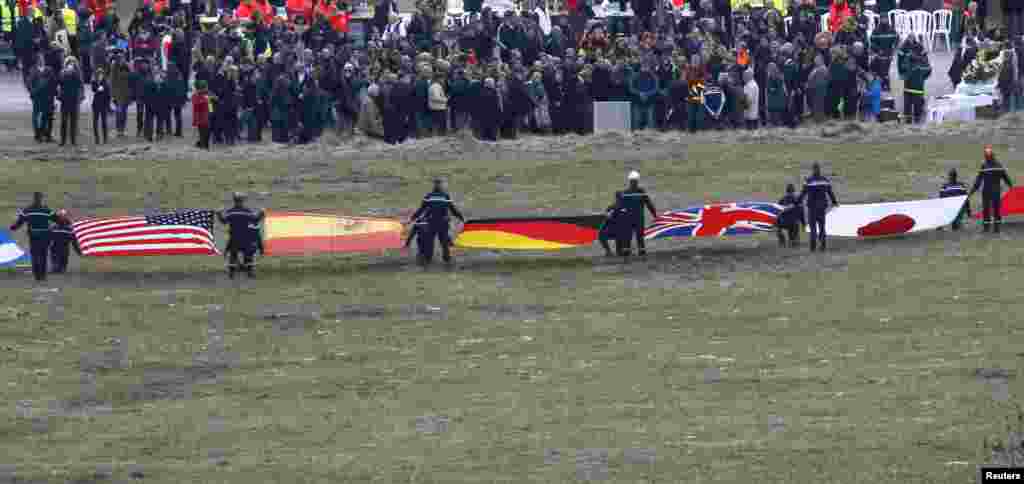 Flags representing some of the nationalities of the victims are seen as family members and relatives gather near the crash site of an Airbus A320 in the French Alps.