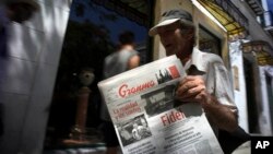FILE - A vendor holds a copy of Cuba's state newspaper, Granma, in Havana, Aug. 13, 2015. 