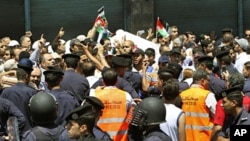 Police stand guard near protesters during a demonstration demanding the dissolution of the parliament and the departure of the government, after Friday prayers in Amman July 15, 2011