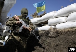 FILE - A Ukrainian soldier looks over sandbags as he stands in a trench close to the small eastern Ukrainian city of Pervomaysk, near Lugansk, Sept. 13, 2014.