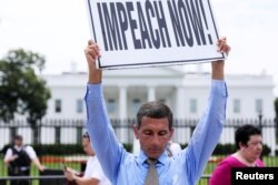 Steve Swanson protests in silence with a sign over his head reading “Impeach Now!” in front of the White House.