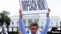 Steve Swanson protests in silence with a sign over his head reading “Impeach Now!” in front of the White House.
