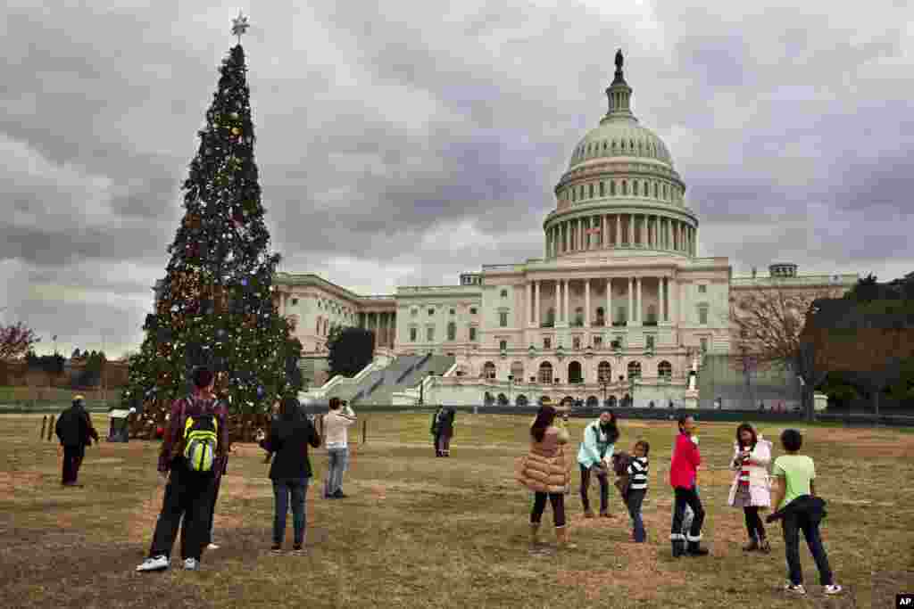 Under rolling clouds, tourists remove their jackets as they visit the U.S. Capitol Christmas tree in Washington, Dec. 22, 2013. 