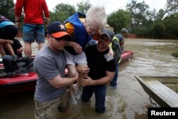 Volunteers help a woman from a rescue boat as it evacuates people from the rising waters of Buffalo Bayou following Hurricane Harvey in a neighborhood west of Houston, Texas, Aug. 30, 2017.
