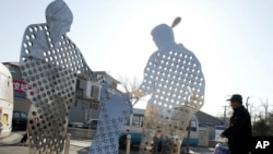 FILE - A man walks past a roadside sculpture which promotes China's one-child policy, in Beijing.