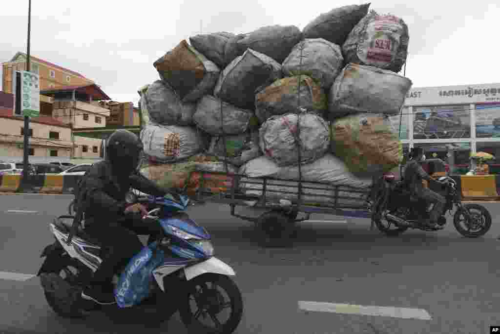 A woman, right, transports huge bags of recyclables in downtown Phnom Penh, Cambodia.