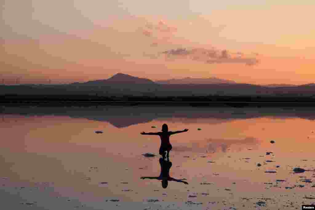 A tourist poses for a photo during the sunset at a salt lake in Larnaca, Cyprus.