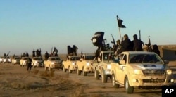 FILE - Militants of the Islamic State group hold up their weapons and wave flags on their vehicles in a convoy on a road leading to Iraq, while riding in Raqqa, Syria. The undated file photo was released by a militant website.
