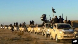 FILE - Militants of the Islamic State group hold up their weapons and wave flags while riding in a convoy in this undated photo near Raqqa, Syria. U.S. war planners believe a simultaneoud assualt on Iraq's Mosul and Syria's Raqqa, both of which have been IS strongholds, would hasten the militants group's fall.