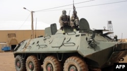 Fighters of the Islamic group, the Movement for Oneness and Jihad in West Africa - an Al-Qaida offshoot - stand guard on a tank abandoned by the Malian Army, near Gao airport, Mali, August 7, 2012.