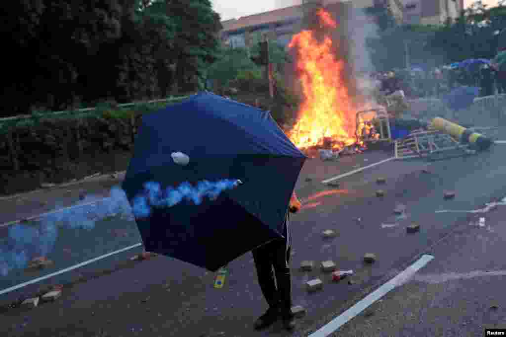 An anti-government protester takes cover under an umbrella during a demonstration in Sha Tin district, on China&#39;s National Day in Hong Kong, China.