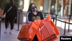 A woman carries Nike shopping bags at the Citadel Outlet mall, as the global outbreak of the coronavirus disease (COVID-19) continues, in Commerce, California, U.S.