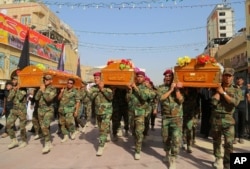 FILE - Members of the Shi'ite group Asaib Ahl al-Haq, or "League of the Righteous," carry coffins of colleagues killed while helping Iraqi security forces battle Islamic State group in Beiji, at a funeral in Najaf, 160 kilometers south of Baghdad, Oct. 18, 2015.