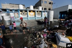 A U.N. worker cleans the garbage at the courtyard of the Abu Hussein U.N. school at Jebaliya refugee camp, northern Gaza Strip, July 30, 2014.