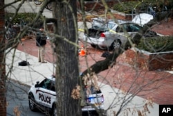 A car sits inside a police line as authorities respond to an attack at Ohio State University, Nov. 28, 2016, in Columbus, Ohio. A man plowed his car into a group of pedestrians and began stabbing people before he was shot to death by a police officer.