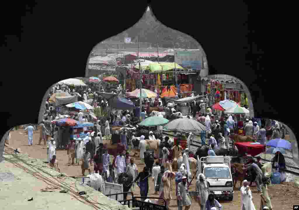 People visiting a cattle market to buy animals for the upcoming Muslim Eid al-Adha, or Feast of Sacrifice holiday, are seen through an arch of a nearby building, in Peshawar, Pakistan.