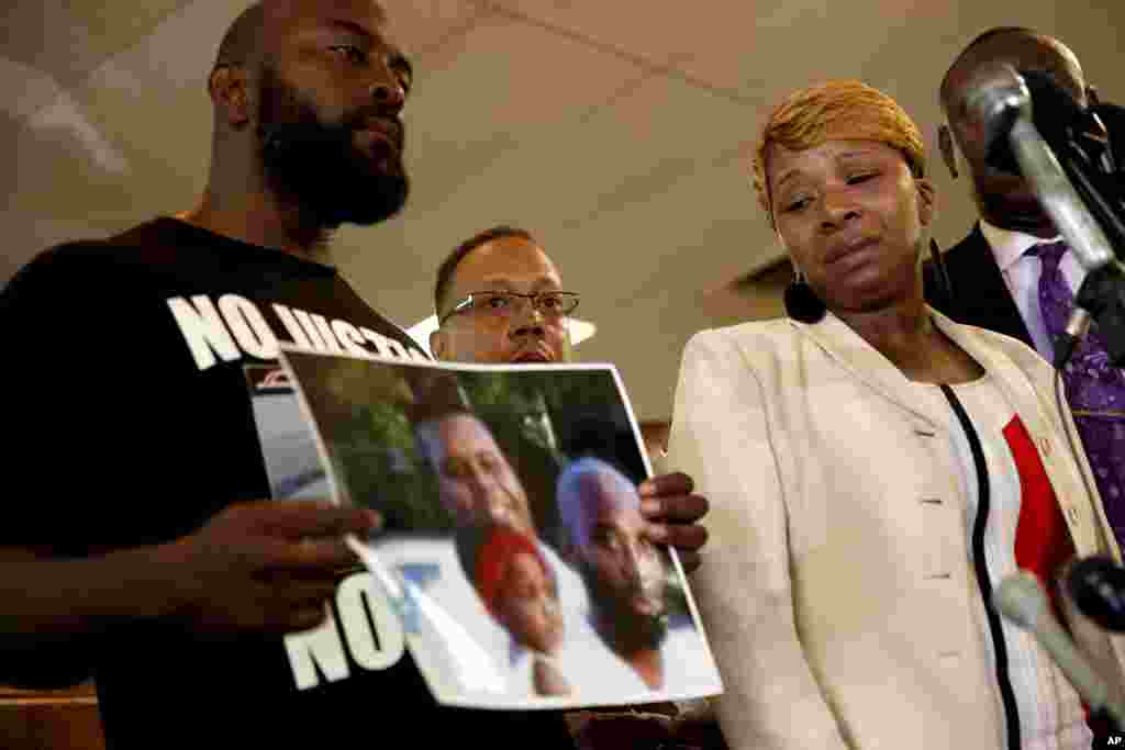 Lesley McSpadden (à direita), mãe do jovem de 18 anos, Michael Brown, ao lado do pai, Michael Brown, que segura uma fotografia de família durante a conferência de imprensa, Ago. 11, 2014.