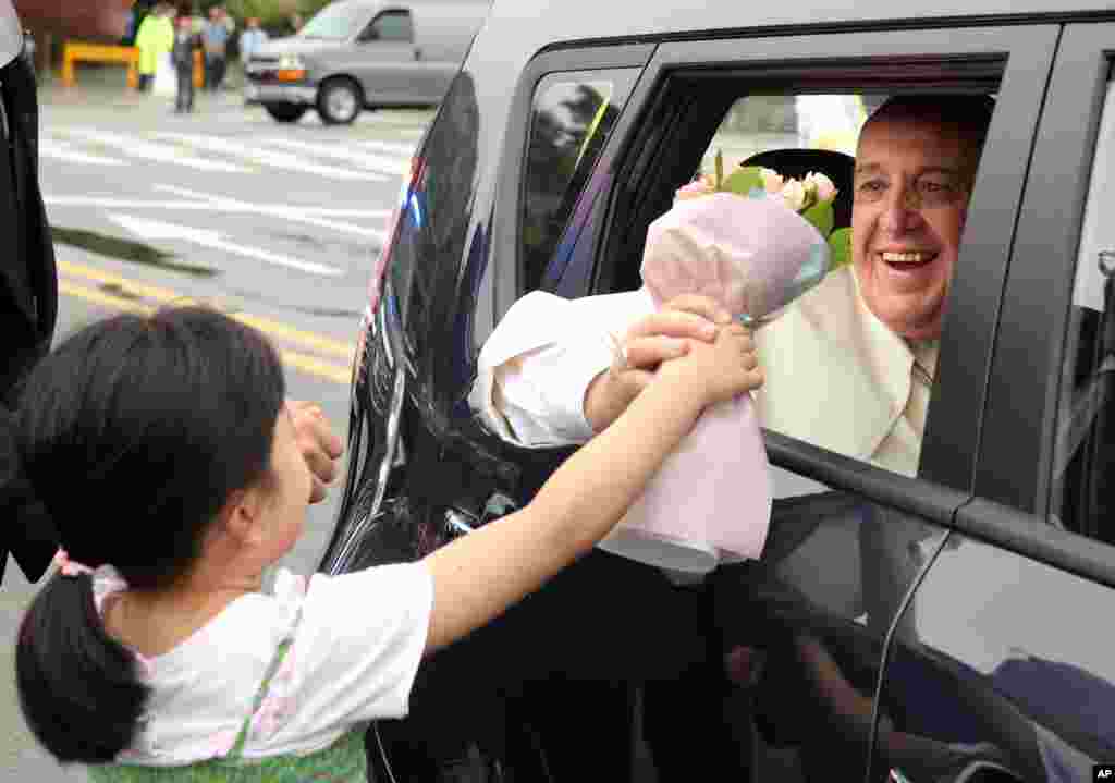 Pope Francis receives a bouquet of flowers from a child as he leaves Seoul at the end of his five-day visit to South Korea, Aug. 18, 2014.