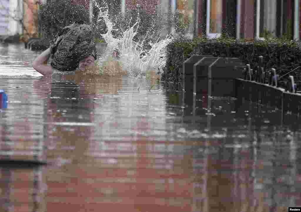 A local resident stumbles as he wades through flood water on a residential street in Carlisle, Britain. British police have declared a major incident in northern England after prolonged heavy rain caused widespread flooding and forced emergency services to evacuate residents from their homes.
