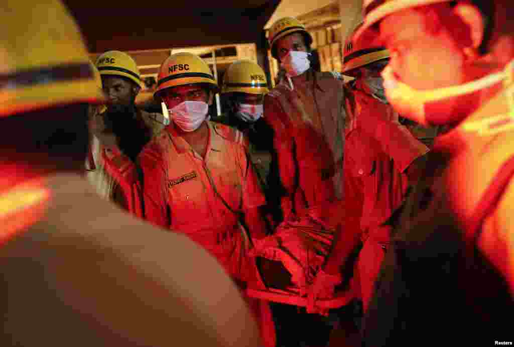 Rescue workers carry a body to an ambulance. The victim was recovered from the debris at the site a collapsed building that was under construction, Canacona, India, Jan. 5, 2014.