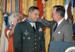 Presiden George Bush meminjamkan kacamatanya kepada ibu negara Barbara Bush saat dia menyematkan Medal of Freedom pada Jenderal Colin Powell, ketua Kepala Staf Gabungan Militer AS (tengah), di Gedung Putih, 3 Juli 1991.